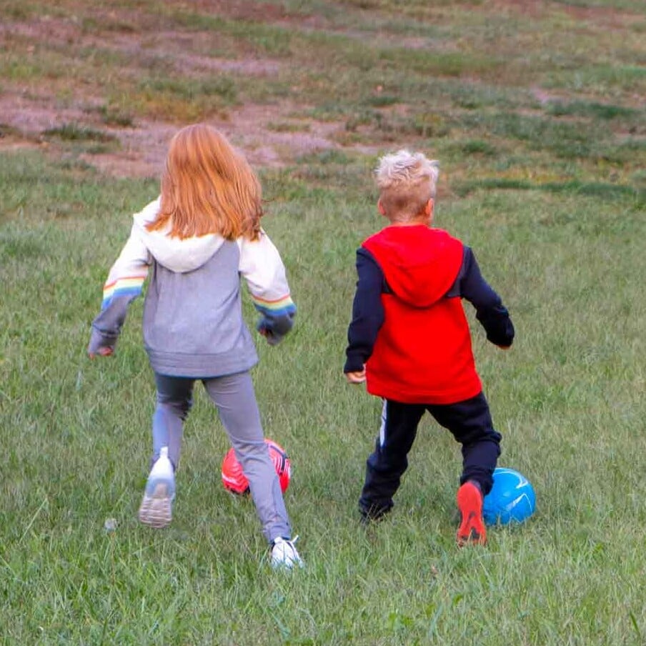 Kids kicking soccer balls in a