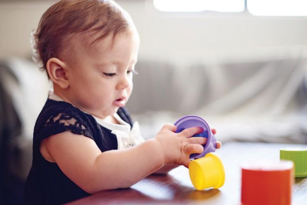Toddler playing with stacking cups at coffee table