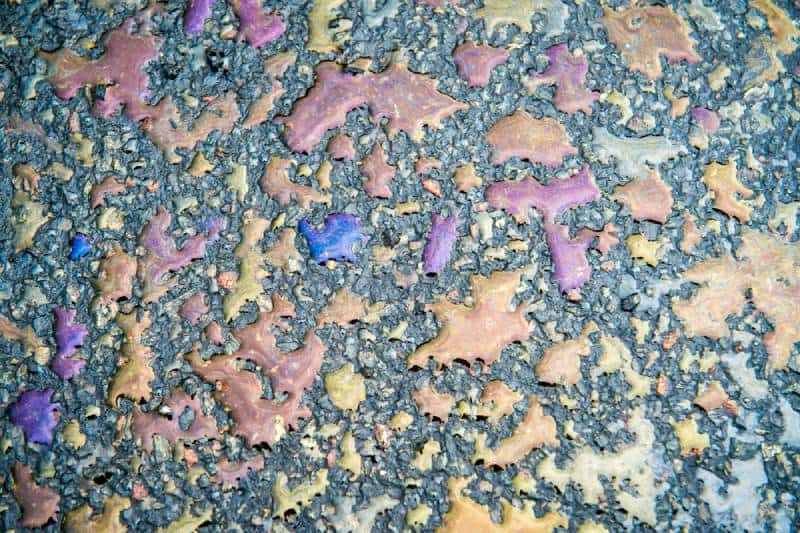oil slick water reflecting rainbow colors on a black asphalt 
