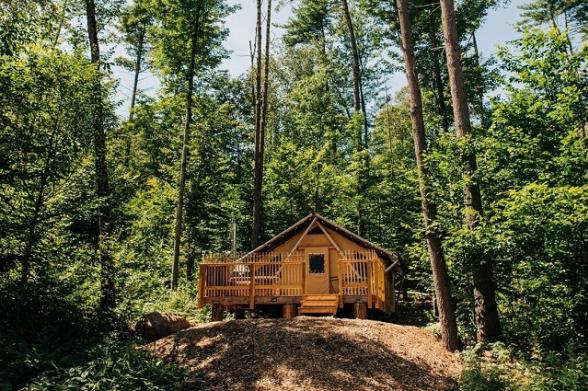 A luxury glamping tent on a raised deck in the Adirondack forest at Huttopia