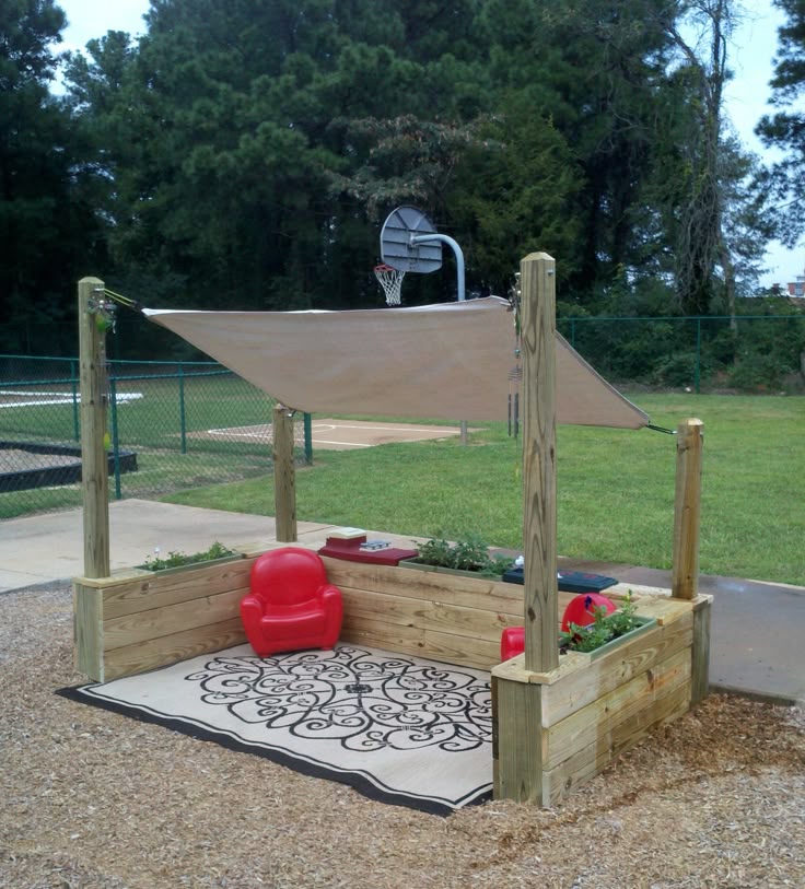 This may contain: an outdoor play area with a basketball hoop and red chair in the middle of it