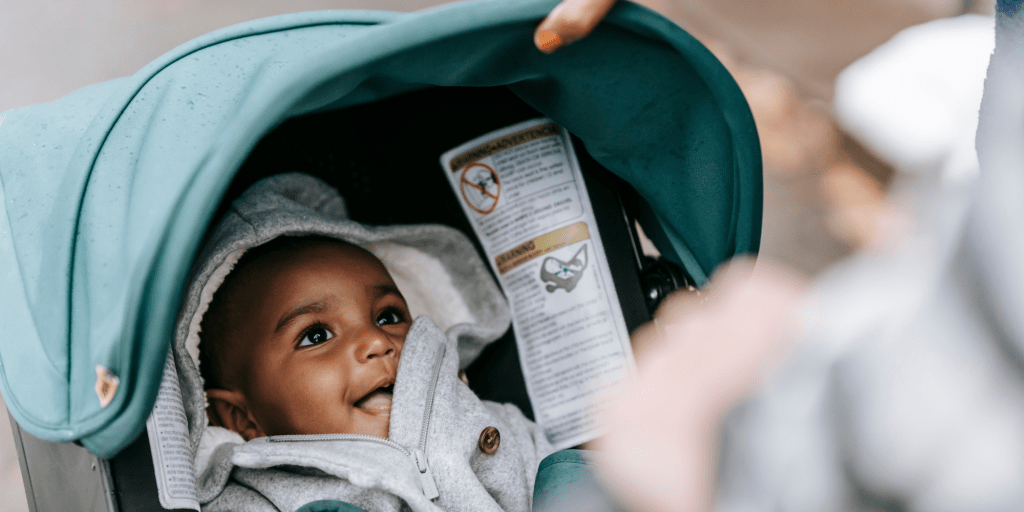 A baby smiles to a caretaker pushing them in a stroller