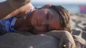 tired little girl laying in the sand on the beach ready to take a nap |  ClipStock