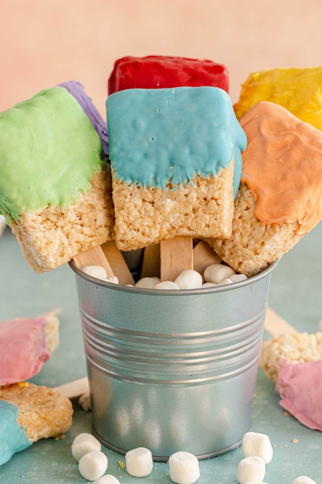Rice krispy treats shaped like paintbrushes in a paint bucket