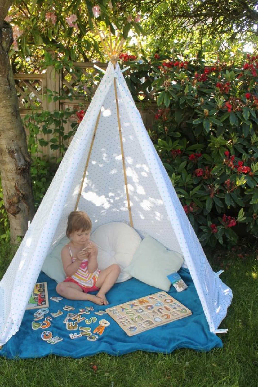 Child sitting in DIY backyard teepee