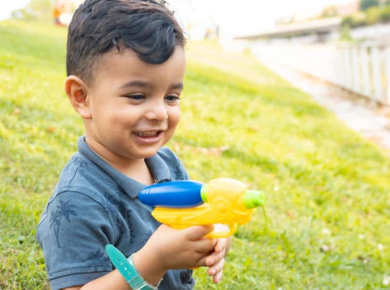 happy little boy playing with a squirt gun outdoors