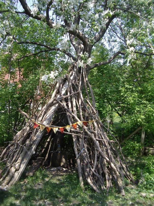 This may contain: a teepee in the middle of some trees with flags hanging from it's branches