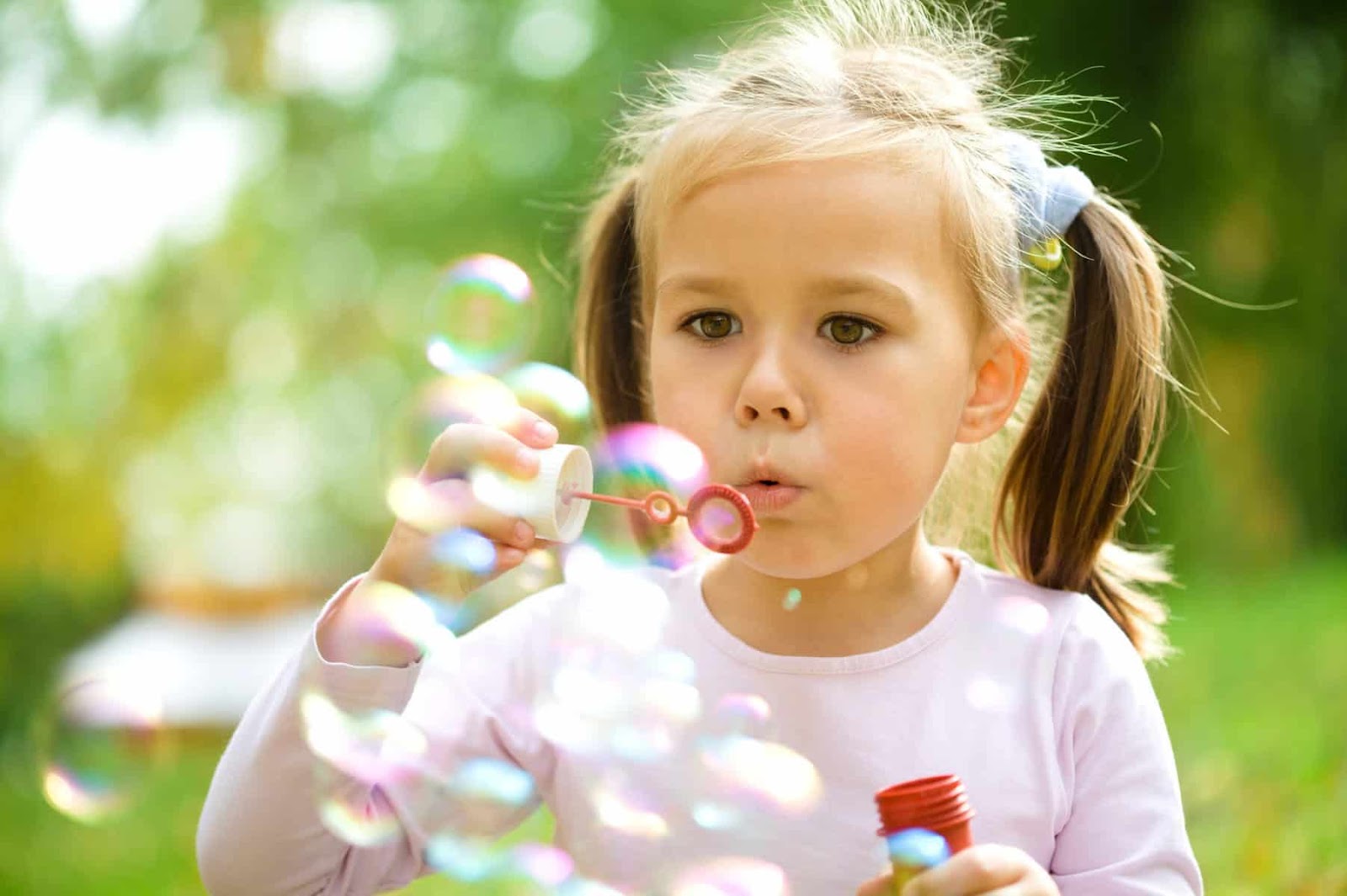 young girl outside blowing bubbles