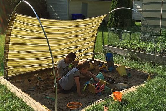 This may contain: two children are playing in the garden with their mother and dad, who is sitting on the ground