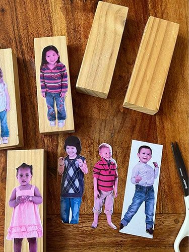 This may contain: several wooden stamps with pictures of children on them and scissors next to them, sitting on a table