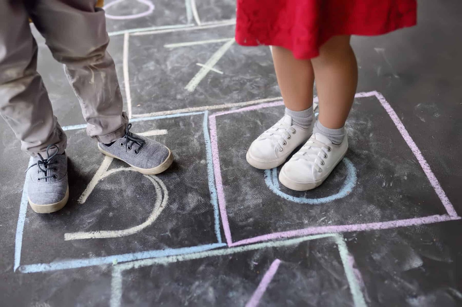 classic outdoor games for kids - hopscotch with two young kids feet on teh board.