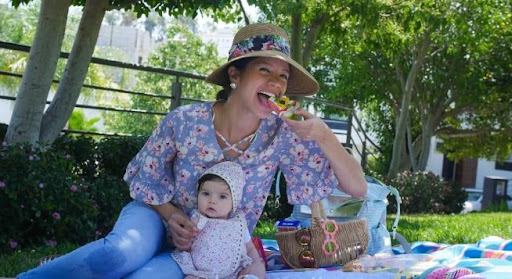This may contain: a woman sitting on the grass with her baby in front of it and text overlay that reads 10 tips for getting outside with baby